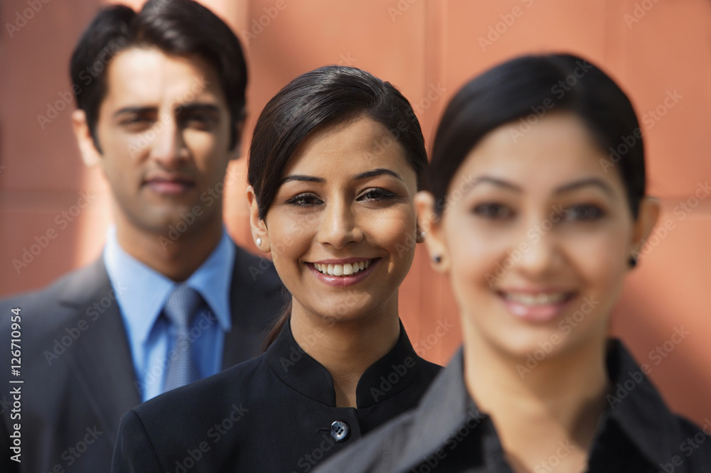 two businesswomen smiling at camera, one businessman (second woman in focus) two businesswomen smiling at camera, one businessman (second woman in focus)