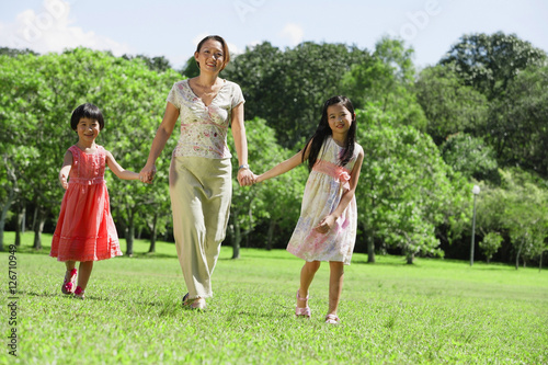 Mother and two daughters holding hands in park