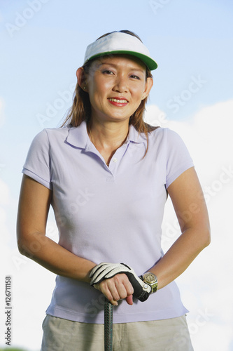Obraz na płótnie Woman wearing sun visor, leaning on golf club w salonie