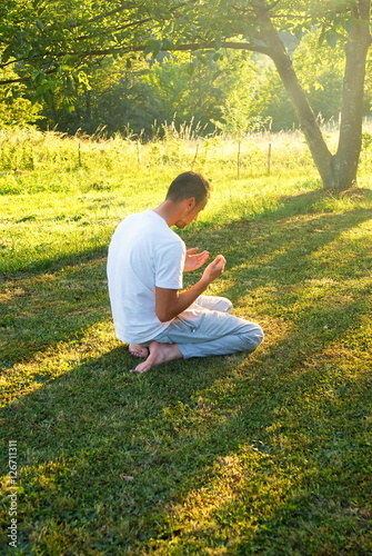 Young Muslim man pray in nature at sunset time