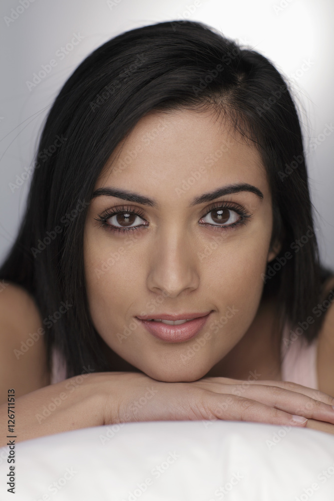 Head shot of young woman resting her chin on hands and smiling Head shot of young woman resting her chin on hands and smiling