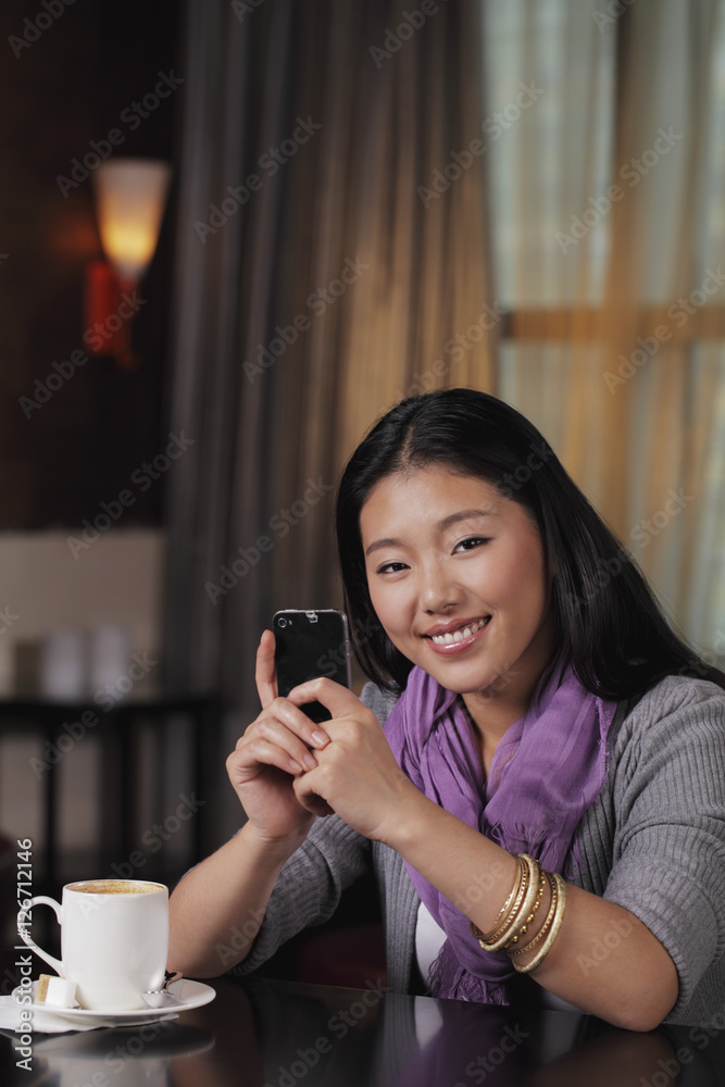 Young woman sitting in restaurant holding phone Young woman sitting in restaurant holding phone
