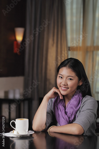 Young woman sitting in cafe with coffee cup © Alexander