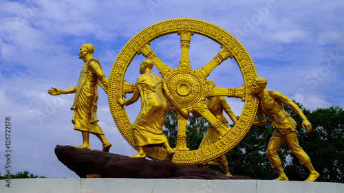 Golden Wheel of Dhamma on sky clouds (Dharmachakra ) Thai Art in public temple Wheel of Dhamma symbol of Buddhism photo