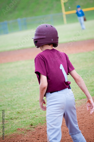 Youth baseball boy on base in maroon jersey