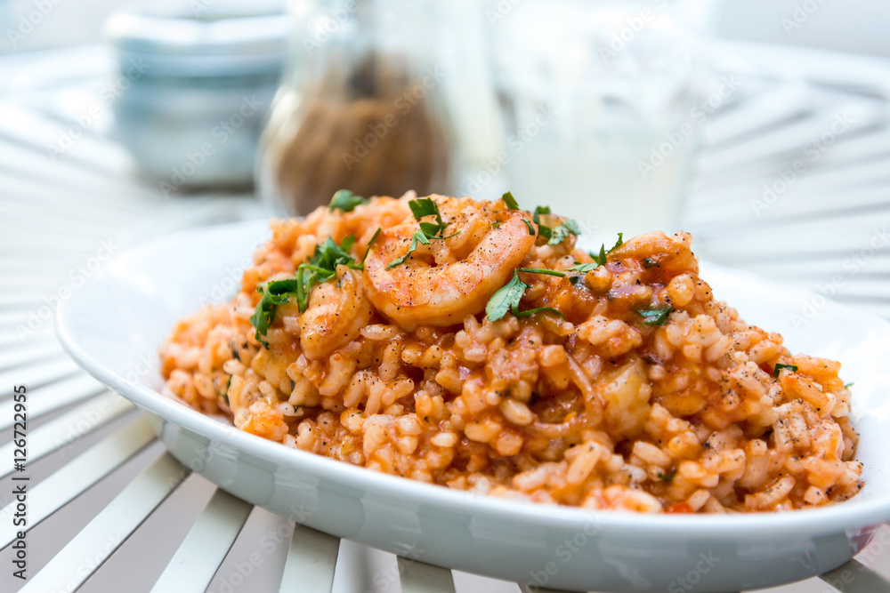 Tasty risotto with Shrimp, fresh herbs vegetables on a white pla Tasty risotto with Shrimp, fresh herbs vegetables on a white pla