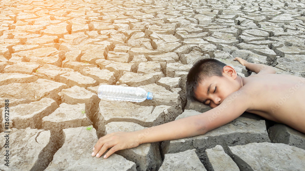 Child lying on cracked earth in the arid area Child lying on cracked earth in the arid area
