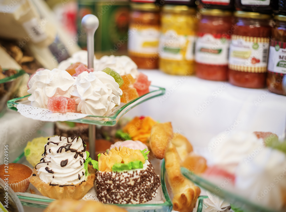 sweet cakes on glass plate for event and jars with fruit jam as