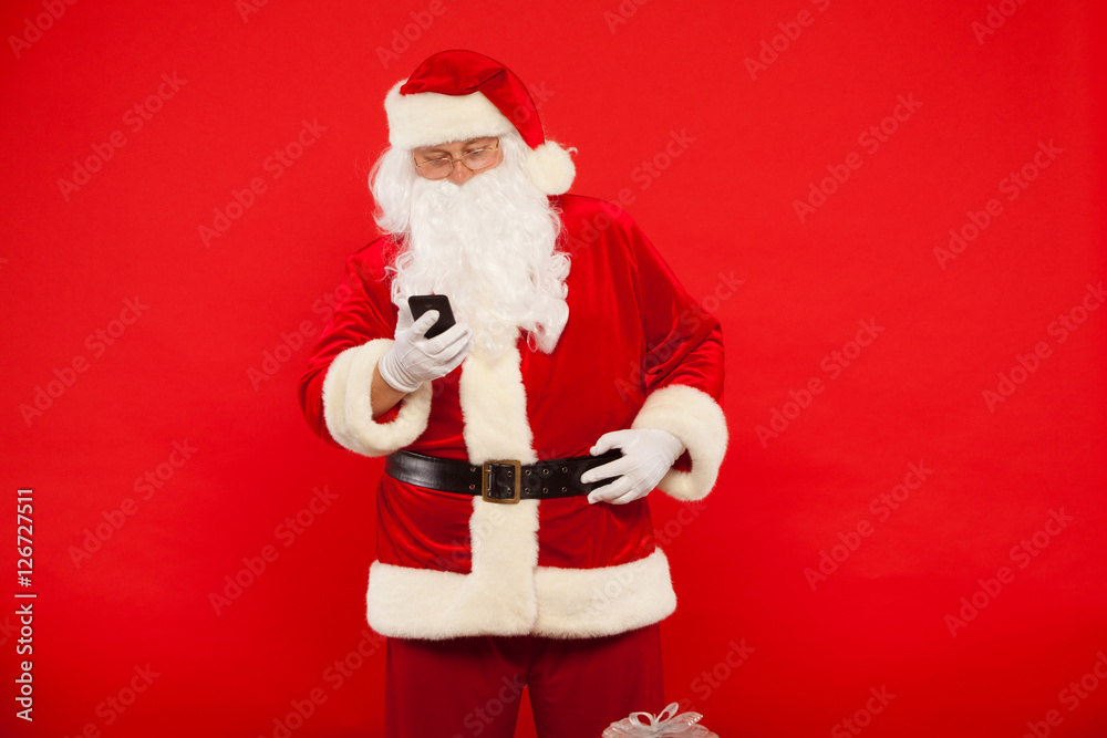 Photo of Santa Claus using mobile phone, on a red background. Christmas Photo of Santa Claus using mobile phone, on a red background. Christmas