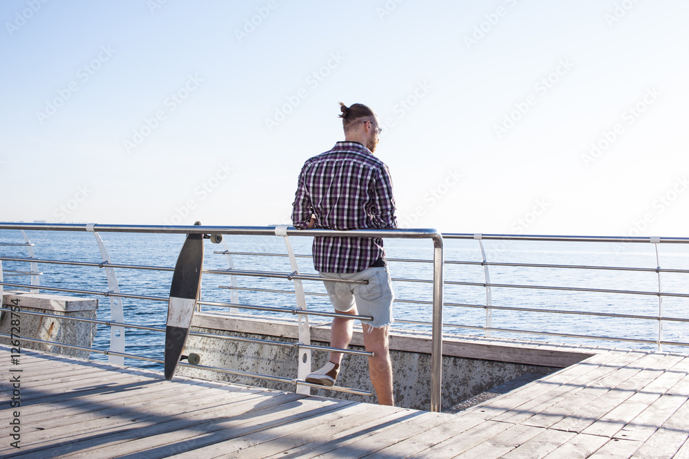 Man with skateboard on the city beach