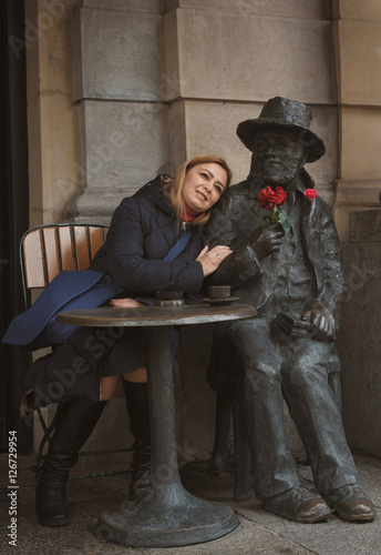 Woman near sculpture of man with flower at table in cafe at Krakow, Poland
