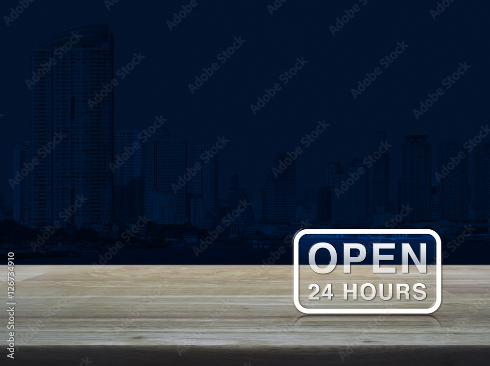 Open 24 hours icon on wooden table over modern office city tower