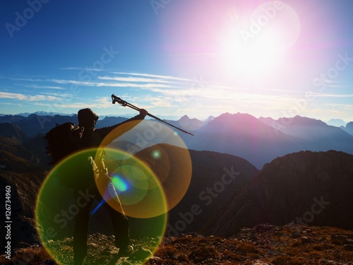 Lens flare defect. all backpacker with poles in hand. Sunny weather in rocky mountains.