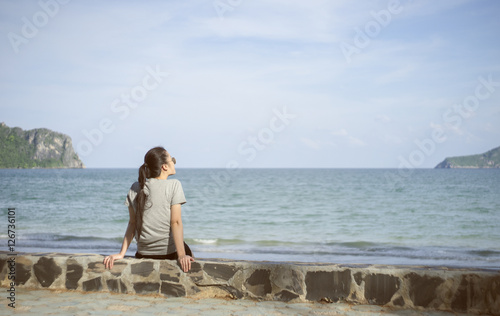 beautiful alone young asian woman at seashore near the beach.blurred sea and sky in background.selective focus.filtered image