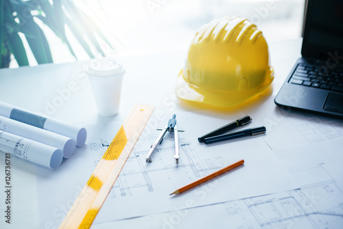 Construction equipment, blueprints and safety helmet on table
