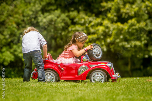 young happy children - boy and girl - driving a toy car outdoors © Alena Yakusheva