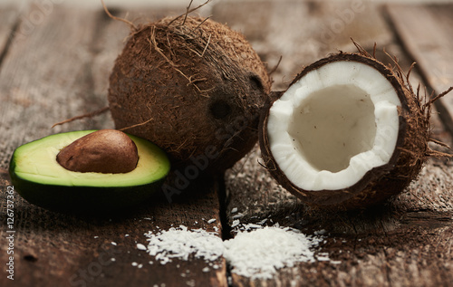 Avocado and broken coconut on dark wood background. Exotic drink ingredients.