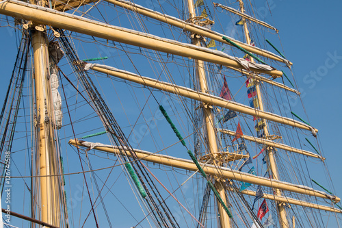 Vintage sailing ship mast ropes and tackle, Tall ship rigging mast detail, blue sky background