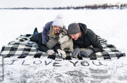 Obraz na płótnie portrait of a young couple with dog lying on snow. w salonie