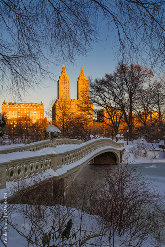 Fototapeta Central Park zimowy wschód słońca na zamarzniętym jeziorze z Bow Bridge i Upper West Side budynków. Manhattan, Nowy Jork
