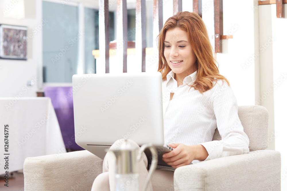 Smiling happy woman sitting on the sofa and using laptop Smiling happy woman sitting on the sofa and using laptop