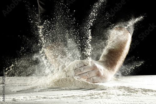 hands and splash of flour with black background
