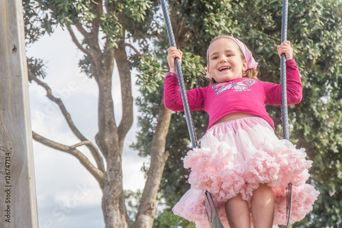 outdoor portrait of young happy child girl swinging on natural b