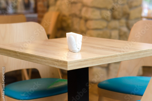 Empty wooden deck table with napkins in white napkin. © valerii kalantai