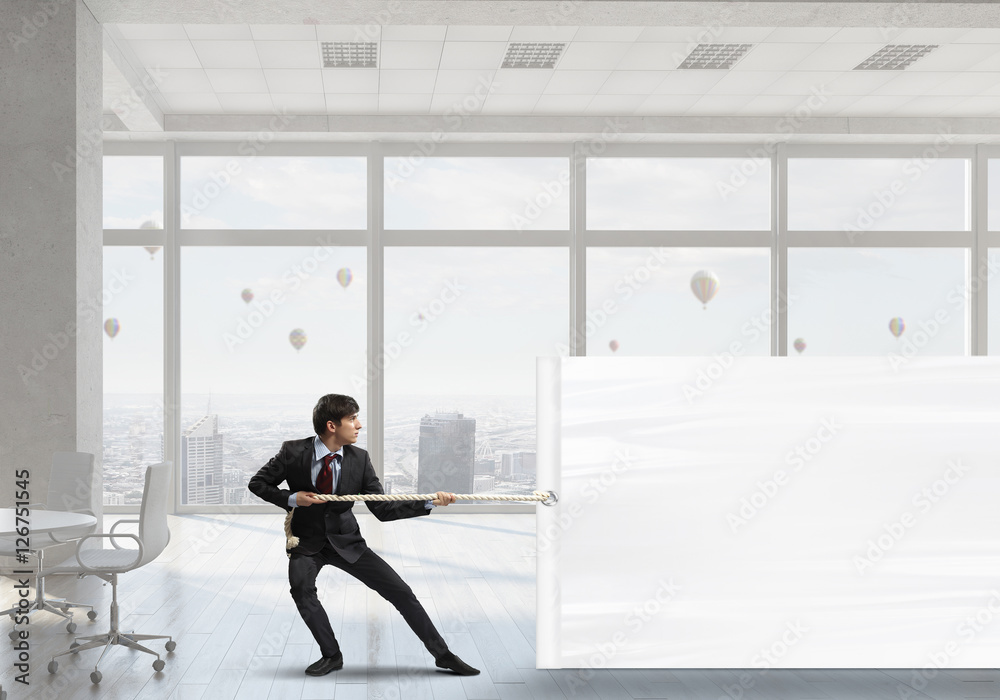 Businessman pulling banner . Mixed media Businessman pulling banner . Mixed media