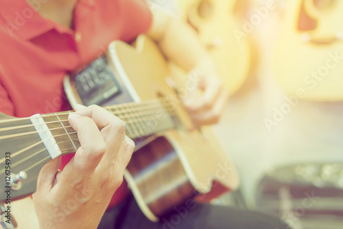 Vintage photo of man is playing guitar with hanging guitars background