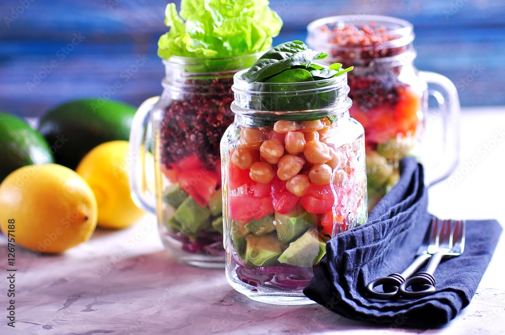 Healthy salad with quinoa and chickpeas, avocado, tomato, red onion, baby spinach, lettuce, olive oil in a Mason jars. Healthy salad with quinoa and chickpeas, avocado, tomato, red onion, baby spinach, lettuce, olive oil in a Mason jars.