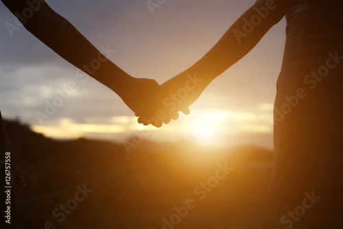  young couple holding hands. In Nature sunrise