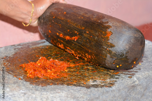 Traditional Sri Lankan way of grinding spices with the grinding stone. Before the electric blenders, the spices were painstakingly ground manually in all houses in Sri Lanka with the grinding stone photo