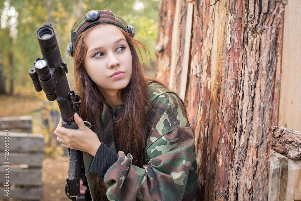 Young girl with a gun peeking from behind cover
