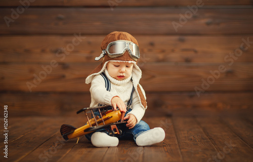 Fotografie funny baby boy pilot aviator with airplane laughing