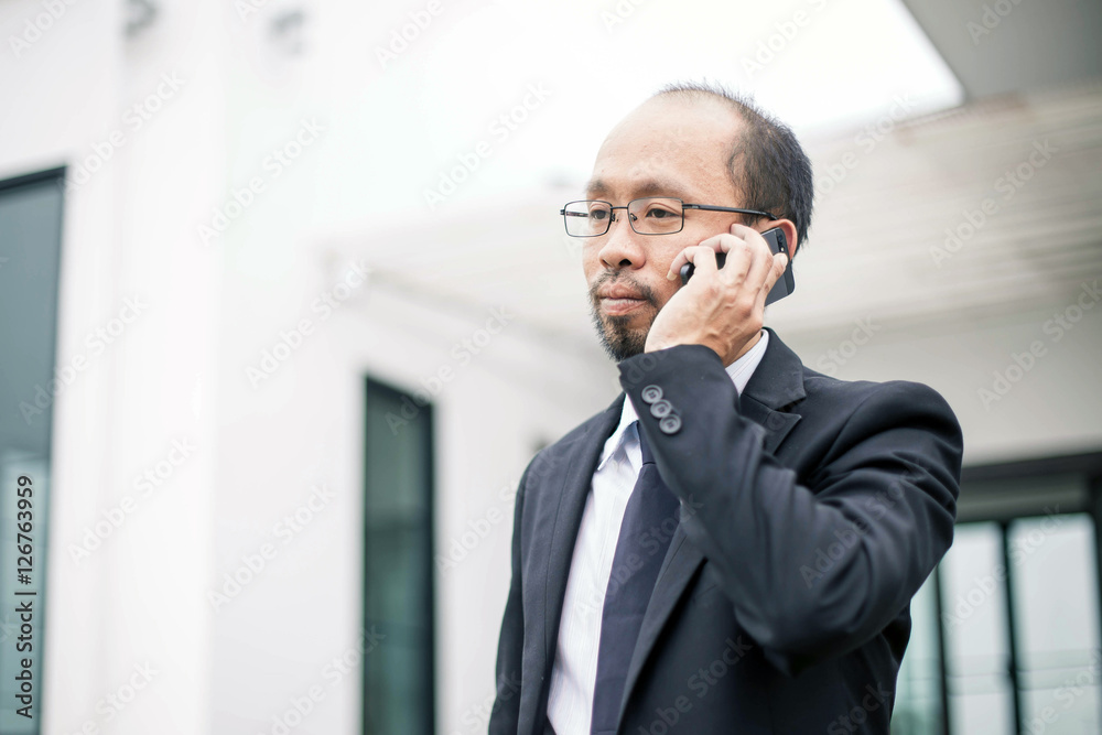business, technology and people concept .Businessman with smartphone talking over office building. Businessman in eyeglasses talking on the phone. business, technology and people concept .Businessman with smartphone talking over office building. Businessman in eyeglasses talking on the phone.