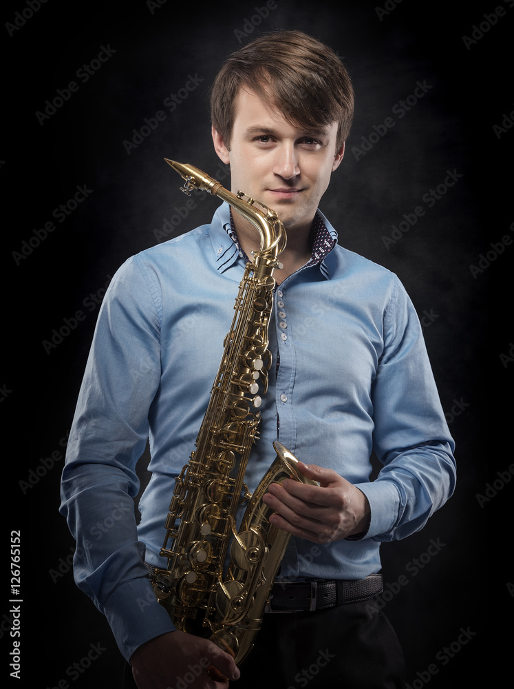 Naklejka premium Attractive saxophonist on a dark background.