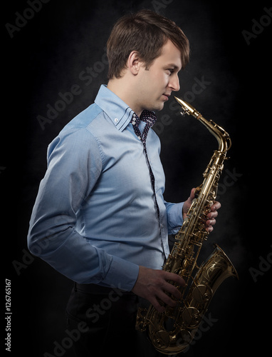 Attractive saxophonist on a dark background.
