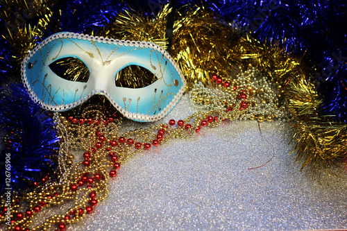 Brilliant blue carnival mask close up on shiny background with festive colored garlands