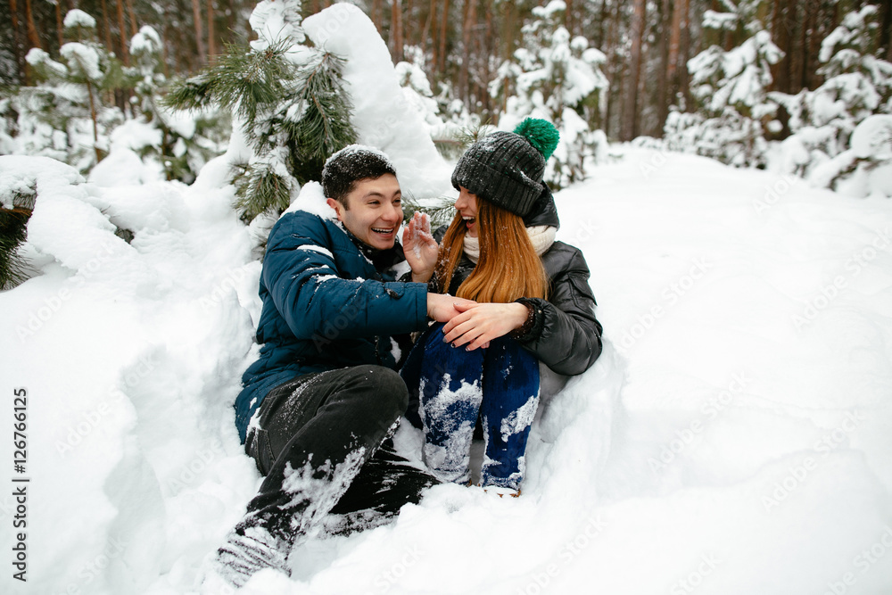 Couple fooling around in the snow under the tree.