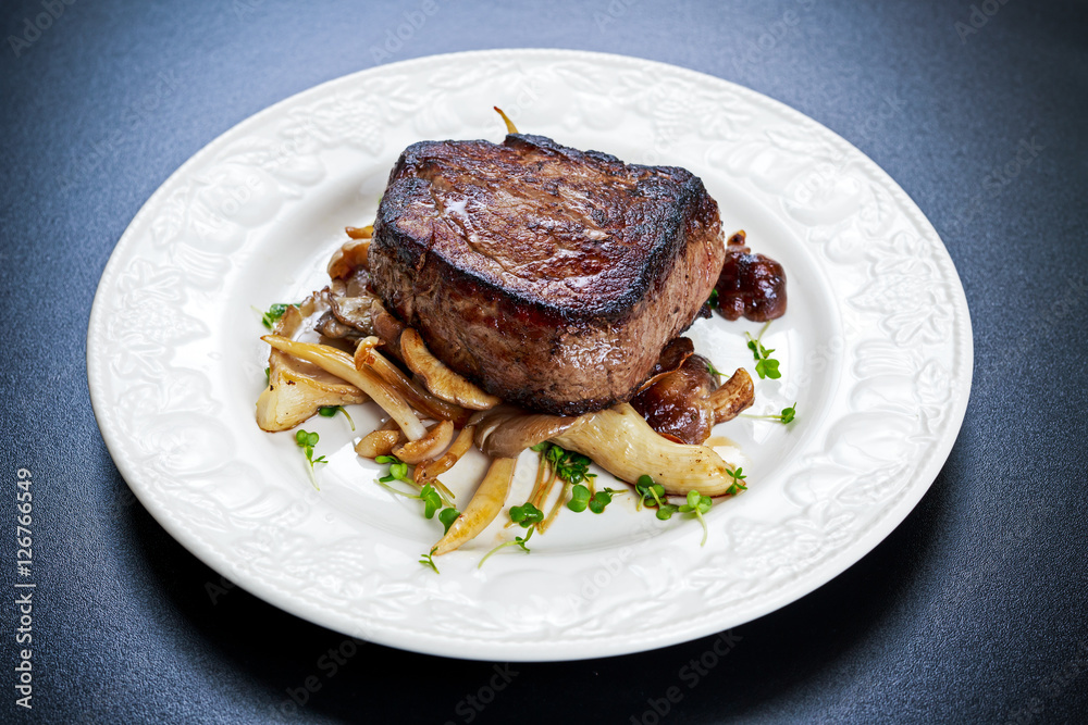 Tasty Beef Mignon steak with mushrooms and herbs on plate. Tasty Beef Mignon steak with mushrooms and herbs on plate.