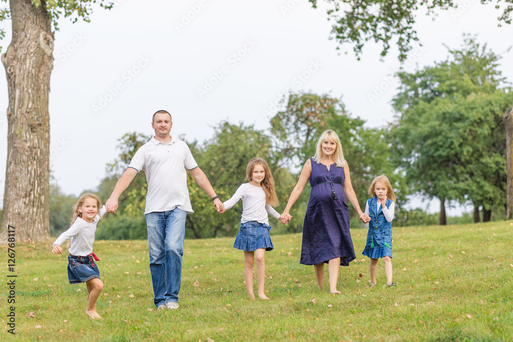 Young pregnant mother with her family in a park