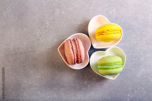 Macarons of different color in a heart shape plates