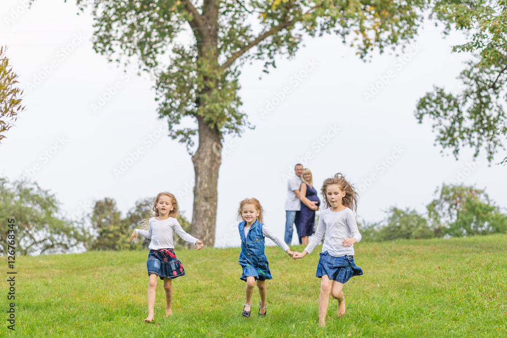 Young pregnant mother with her family in a park