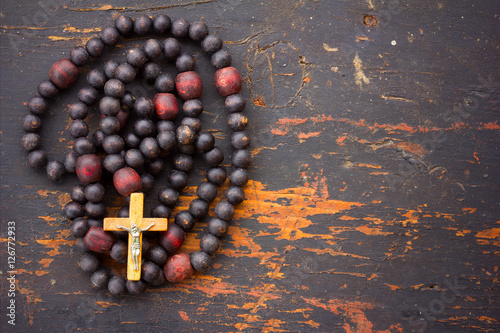 Fotografija Christian rosary prayer with a cross on old black wooden background with space for text