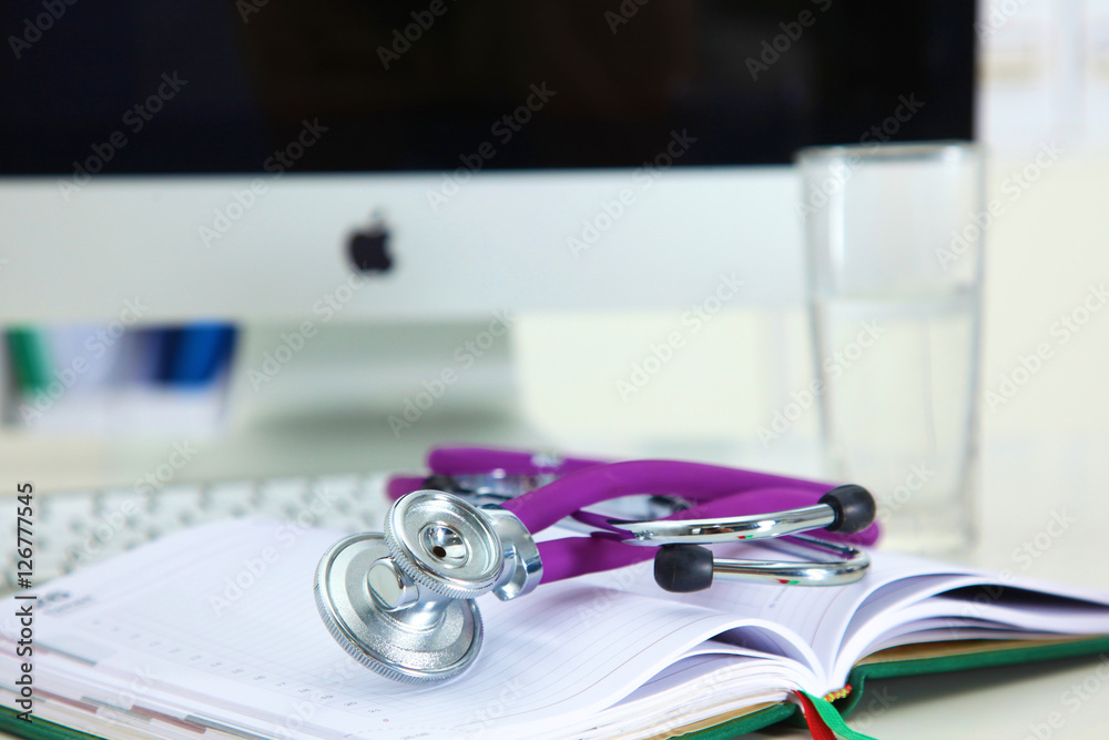 Stethoscope lying on a table an open book Stethoscope lying on a table an open book