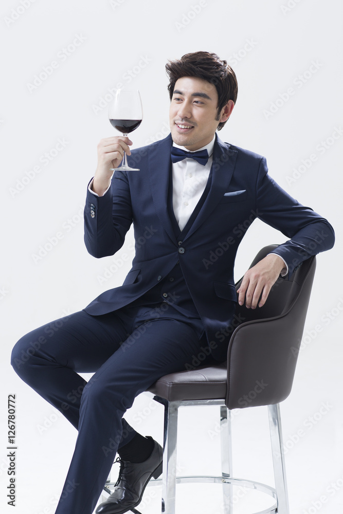 Man holding wine glass while sitting on chair foto de Stock | Adobe Stock