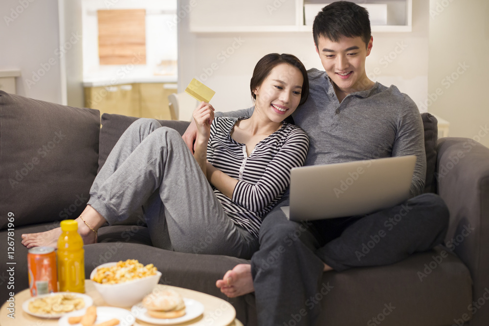 Young couple using laptop while doing online shopping at home Young couple using laptop while doing online shopping at home