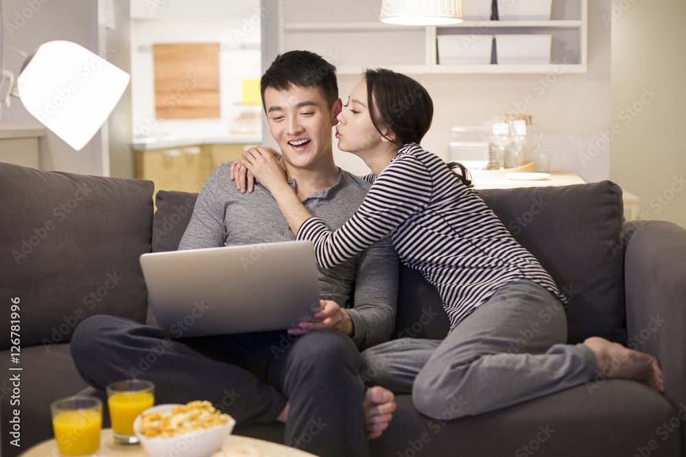 Young couple using laptop on living room sofa Young couple using laptop on living room sofa