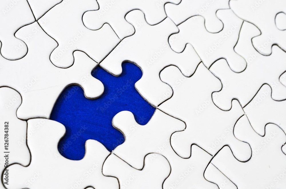 A top view image of a white jigsaw puzzle with a missing piece. A top view image of a white jigsaw puzzle with a missing piece.